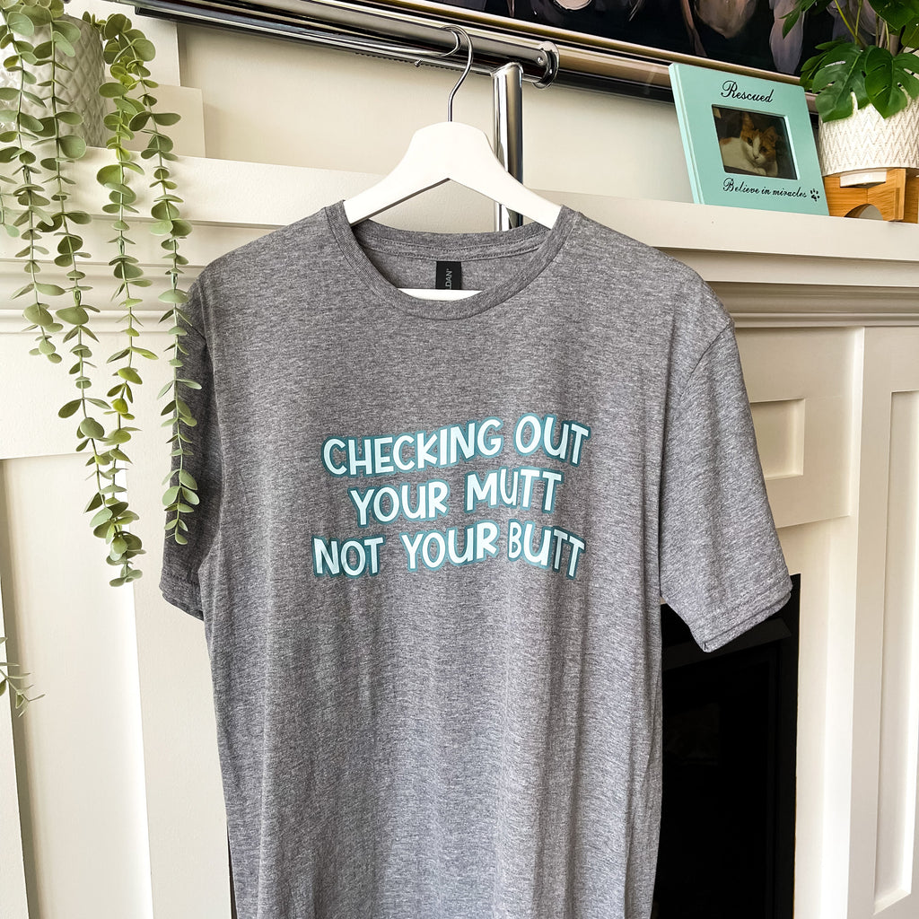 Gray t-shirt with humorous text on a hanger in front of a fireplace.
