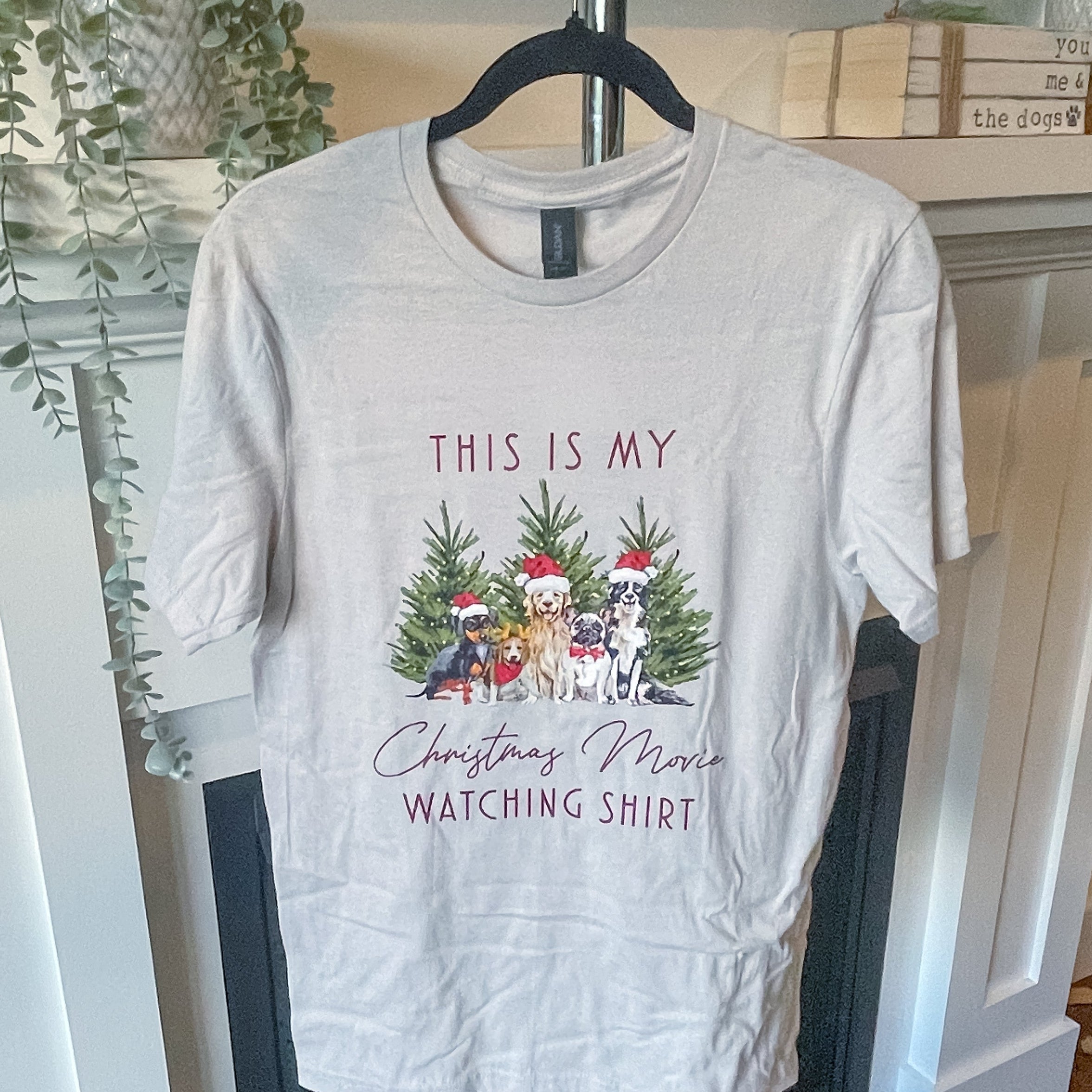 White t-shirt with Christmas-themed design on a hanger in a room.