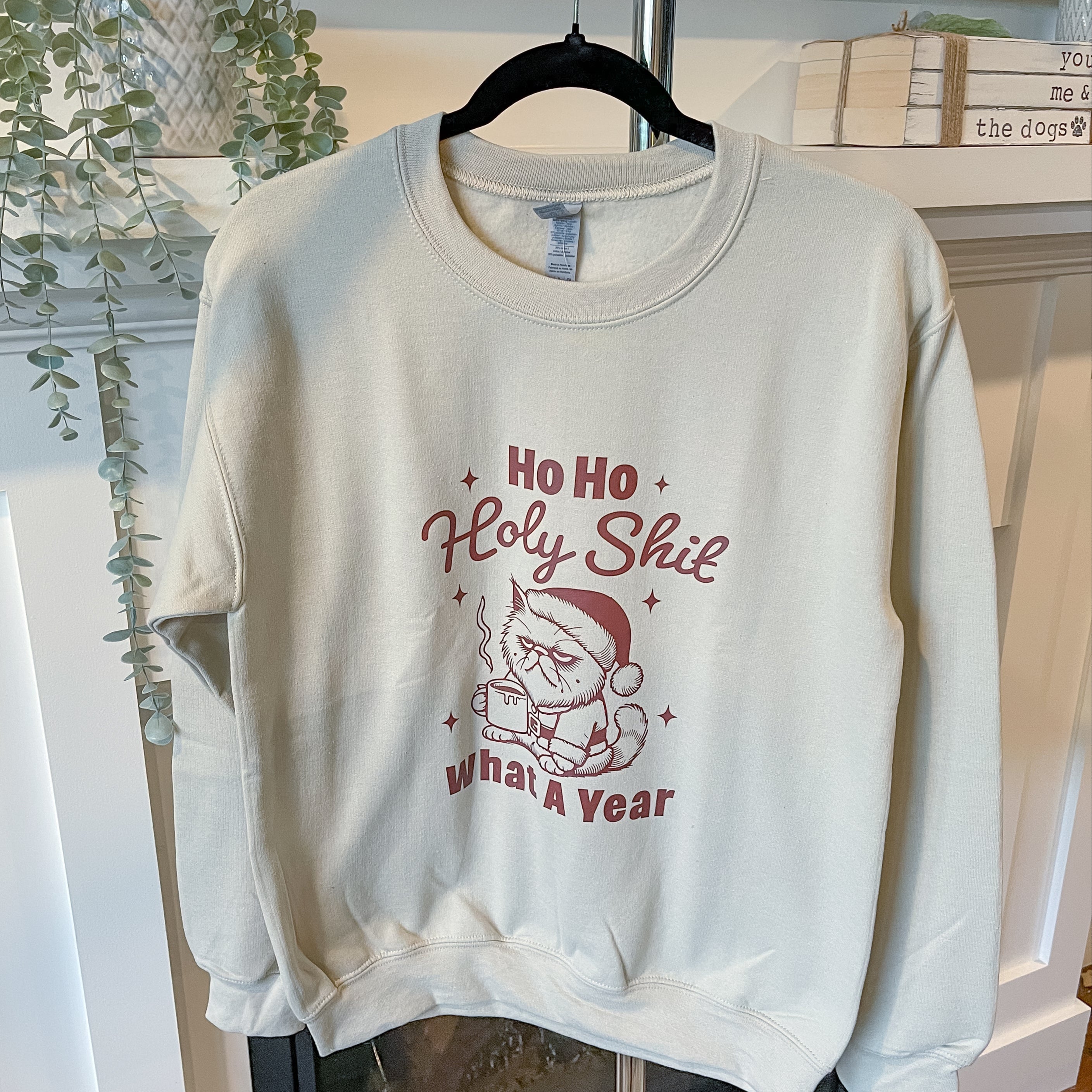 White sweatshirt with Christmas-themed text and graphics on a hanger.